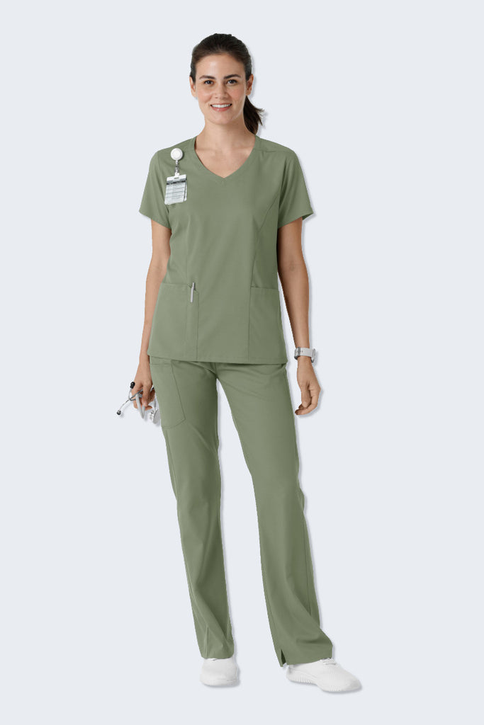 Woman wearing a sage green scrub set from WonderWink Boundless, including the 6151 Women's V-neck Scrub Top and 5251 Women's Bootcut Scrub Pants. This set offers a stylish, contemporary look with soft, breathable, and eco-friendly fabric, ensuring comfort and flexibility during a busy workday. Supplied by Infectious Clothing Co.