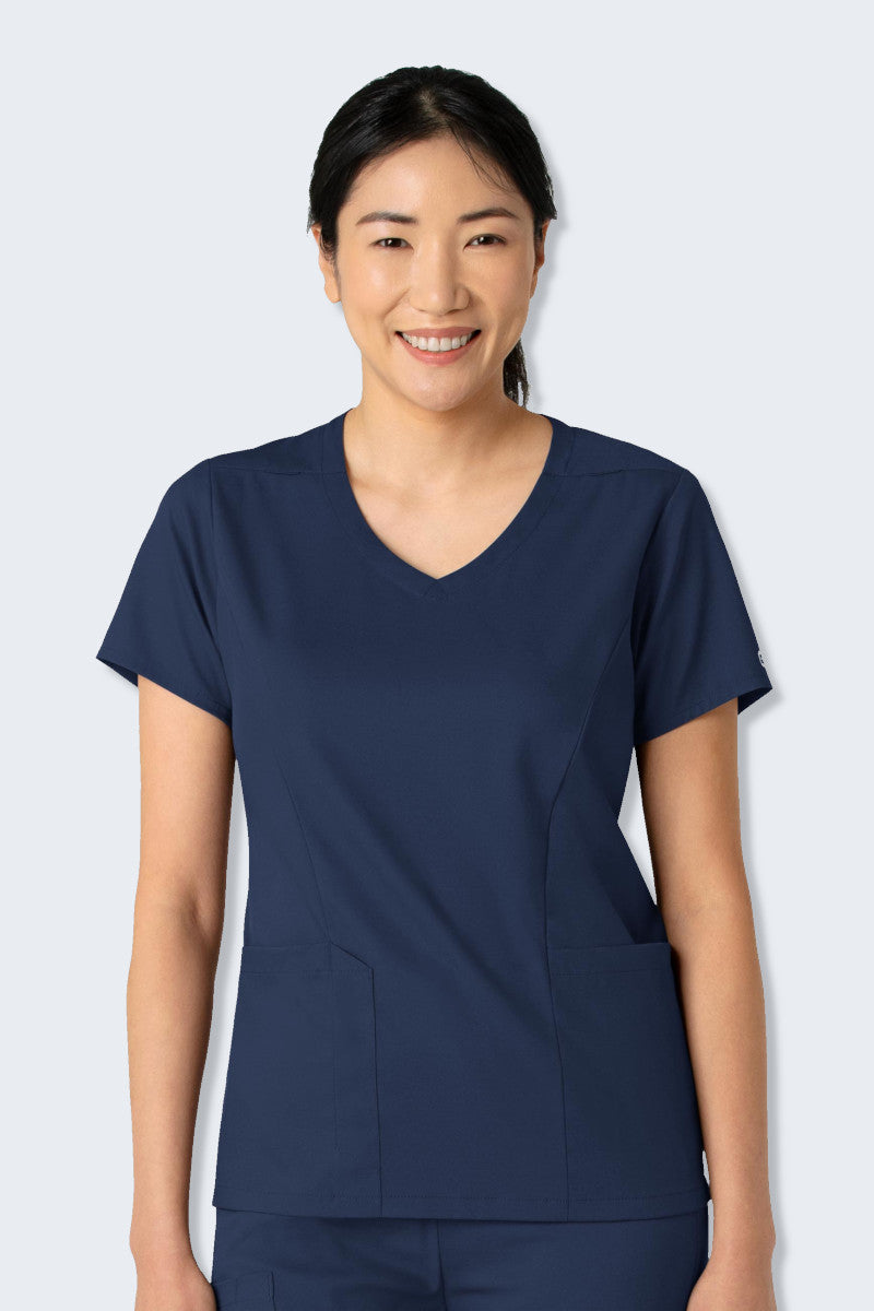 Nurse wearing the WonderWink Boundless 6251 V-neck Scrub Top in Navy, featuring a classic neckline, two top-loading pockets with a pen slot and phone pocket, and a curved hem for a modern, flattering fit. Made from soft, stretchy, and sustainable fabric, ideal for healthcare professionals. Supplied by Infectious Clothing Co.