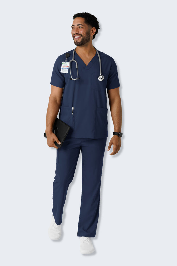 A male Doctor wearing a navy scrub set from WonderWink Boundless, featuring the 6351 Men's V-neck Scrub Top and 5351 Men's Straight-Leg Scrub Pants. The set offers a modern, professional look with soft, stretchy, and sustainable fabric, providing comfort and functionality for healthcare professionals throughout the workday. Supplied by Infectious Clothing Co.