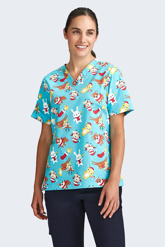 Female model wearing a light blue Christmas scrub top from Infectious Clothing Company, featuring playful holiday-themed prints of Santa, reindeer, and festive animals. Perfect for healthcare professionals bringing holiday cheer to the workplace.