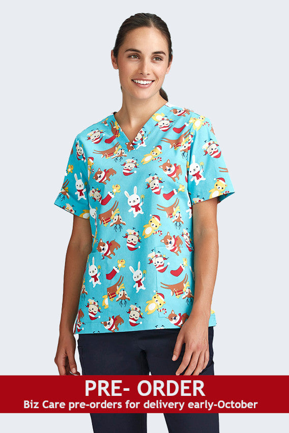 Female model wearing a light blue Christmas scrub top from Infectious Clothing Company, featuring playful holiday-themed prints of Santa, reindeer, and festive animals. Perfect for healthcare professionals bringing holiday cheer to the workplace.