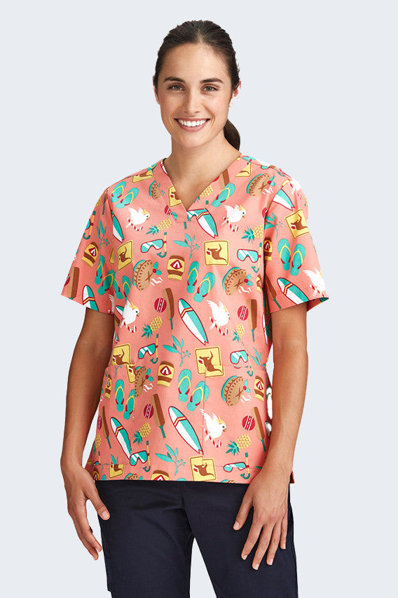 Female model wearing a coral scrub top from Infectious Clothing Company, featuring fun, summery prints with beach themes, including surfboards, sunglasses, and beach animals. Ideal for healthcare professionals who want a cheerful, summery look.