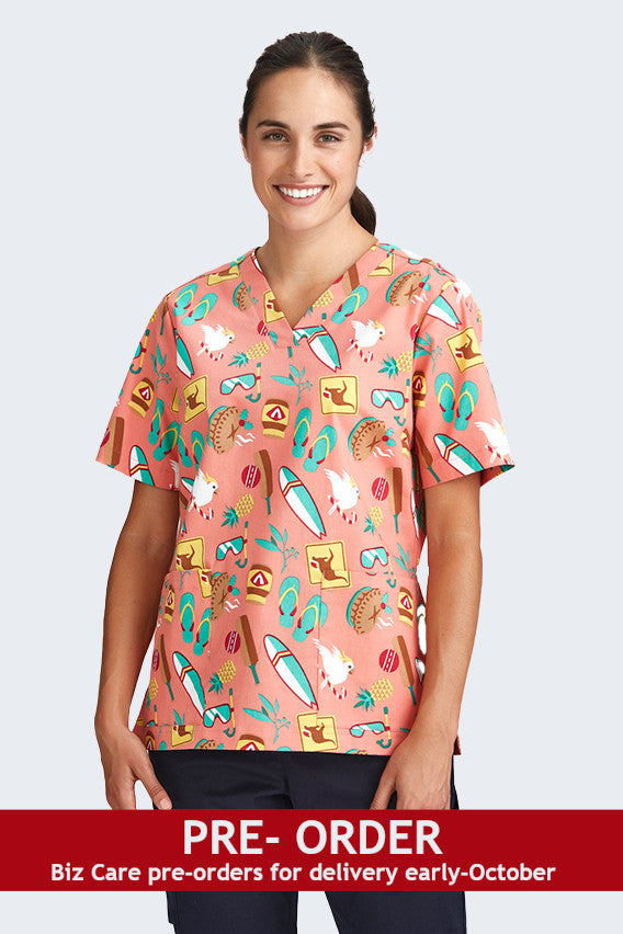 Female model wearing a coral scrub top from Infectious Clothing Company, featuring fun, summery prints with beach themes, including surfboards, sunglasses, and beach animals. Ideal for healthcare professionals who want a cheerful, summery look.