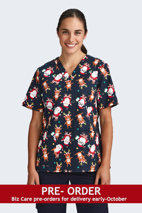 Female model wearing a navy blue Christmas scrub top from Infectious Clothing Company, featuring cute prints of Santa and reindeer. This festive scrub top is perfect for healthcare professionals looking to add holiday spirit to their work attire.