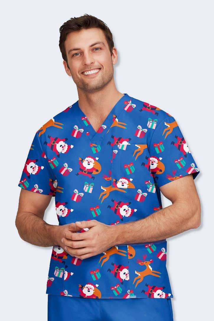 Male model wearing the 'Joyous Santa' Christmas scrub top from Infectious Clothing Company, featuring a playful Santa and reindeer print on a vibrant blue background. This festive scrub top is perfect for healthcare professionals during the holiday season, providing comfort and durability while celebrating in style. Ideal for those seeking quality Christmas scrubs.