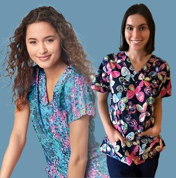 Two women wearing colourful printed scrub tops. The woman on the left has curly hair and is wearing a blue and pink mosaic-patterned scrub top. The woman on the right has short hair and is wearing a scrub top with a bold, multicoloured heart design. Both are smiling in the side-by-side image. Infectious Clothing Co